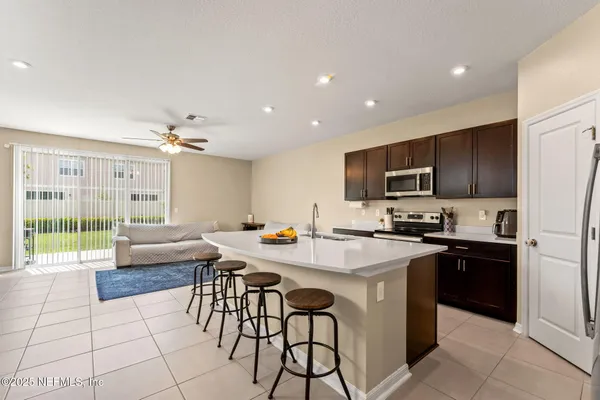 a kitchen with kitchen island granite countertop a stove a sink a microwave a dining table and chairs with wooden floor