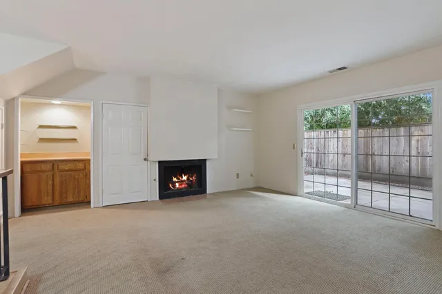 a view of empty room with floor to ceiling window and fireplace