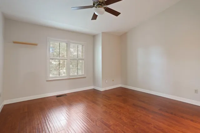 an empty room with wooden floor cabinet and windows