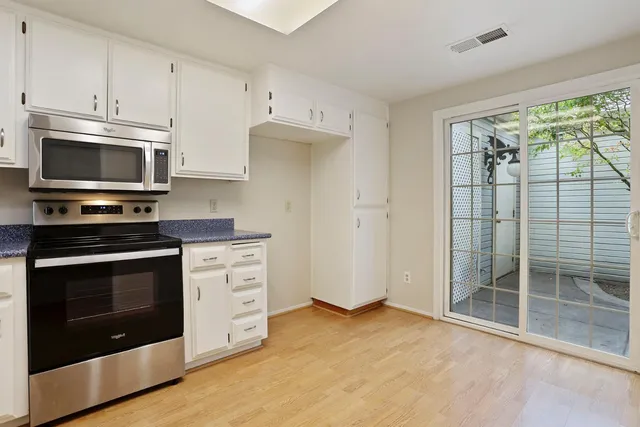a kitchen with stainless steel appliances white cabinets and a stove top oven