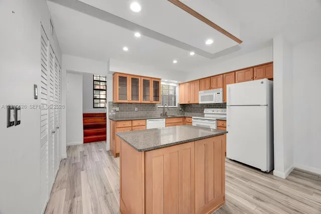 a kitchen with stainless steel appliances granite countertop a refrigerator a stove and a wooden floors