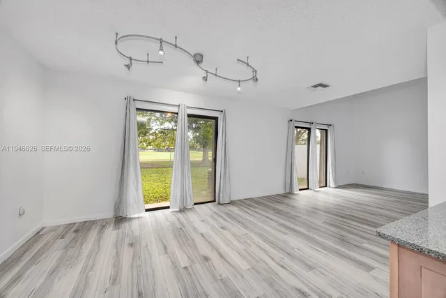 a view of an empty room with a window and wooden floor