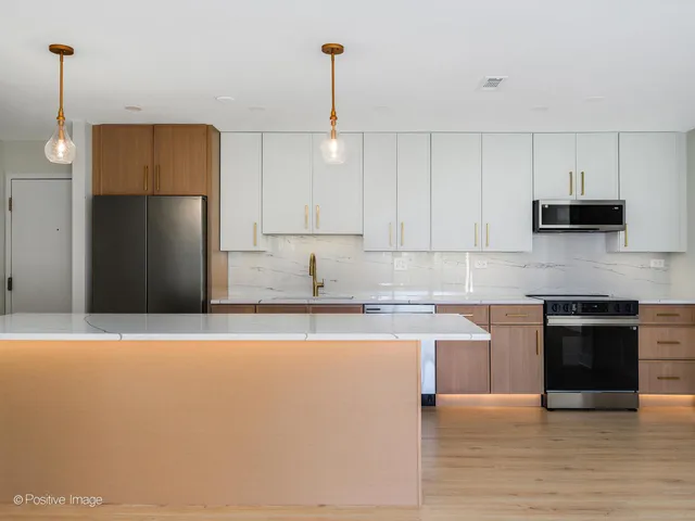 a kitchen with stainless steel appliances granite countertop a refrigerator a sink a stove and oven with wooden floor