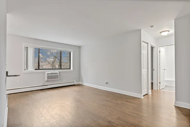 an empty room with wooden floor and window