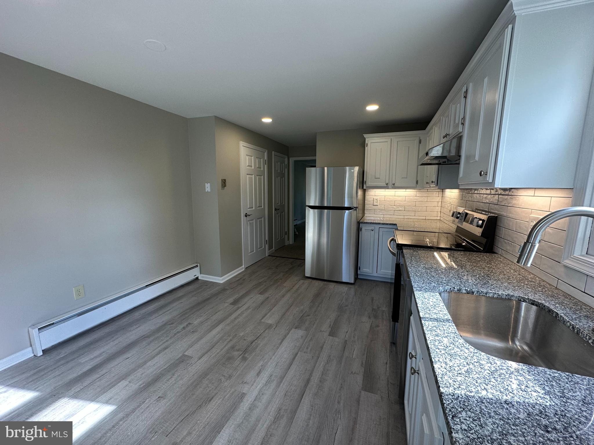 134 A Maple Avenue Dublin, PA 18917 - Photo 3 of 23 a kitchen with stainless steel appliances granite countertop a refrigerator a sink dishwasher a stove and white countertops with wooden floor