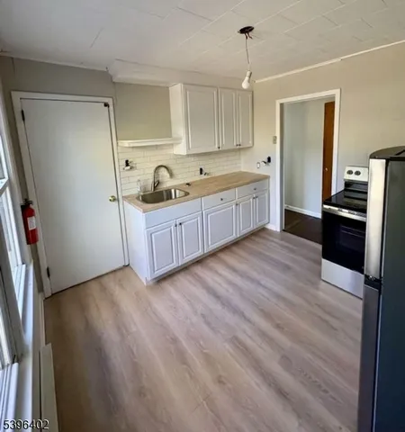 a kitchen with stainless steel appliances granite countertop a refrigerator a sink dishwasher a stove and white countertops with wooden floor