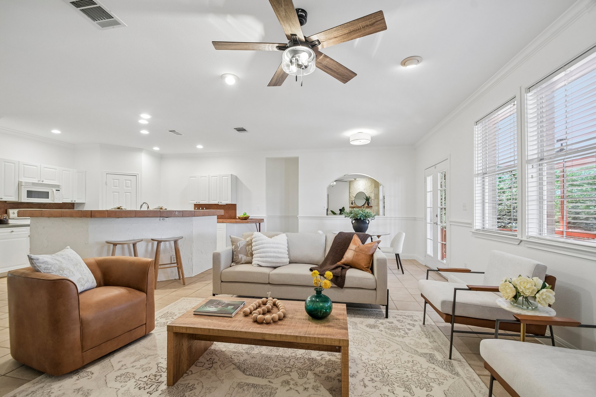20609 Bridle Path Road Lago Vista, TX 78645 - Photo 11 of 30 An inviting, naturally illuminated living room flows seamlessly into the kitchen, showcasing modern amenities and elegant tile flooring.