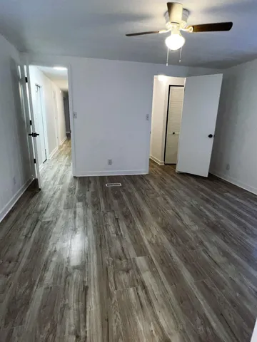 an empty room with wooden floor and a ceiling fan