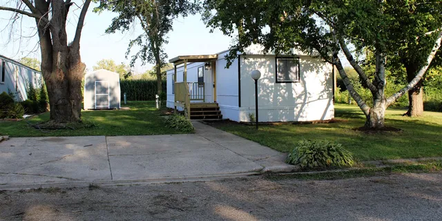 a view of a white house with a large tree