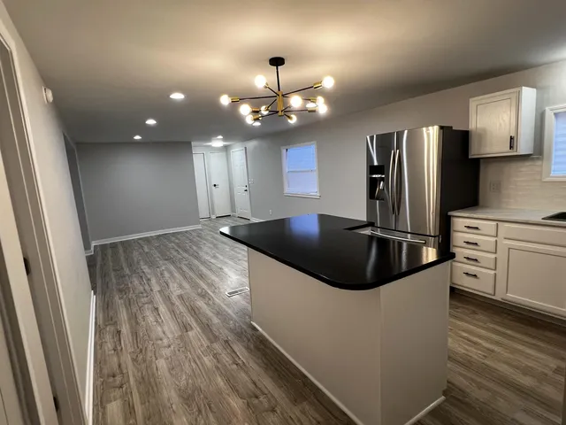 a kitchen with stainless steel appliances kitchen island granite countertop a sink and refrigerator