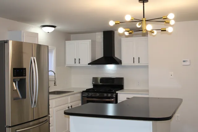 a kitchen with stainless steel appliances granite countertop a sink a refrigerator and a stove