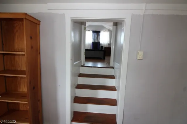 a view of a hallway with wooden floor and a bathroom
