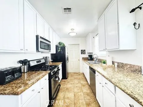 a kitchen with kitchen island granite countertop a sink a counter top space appliances and cabinets