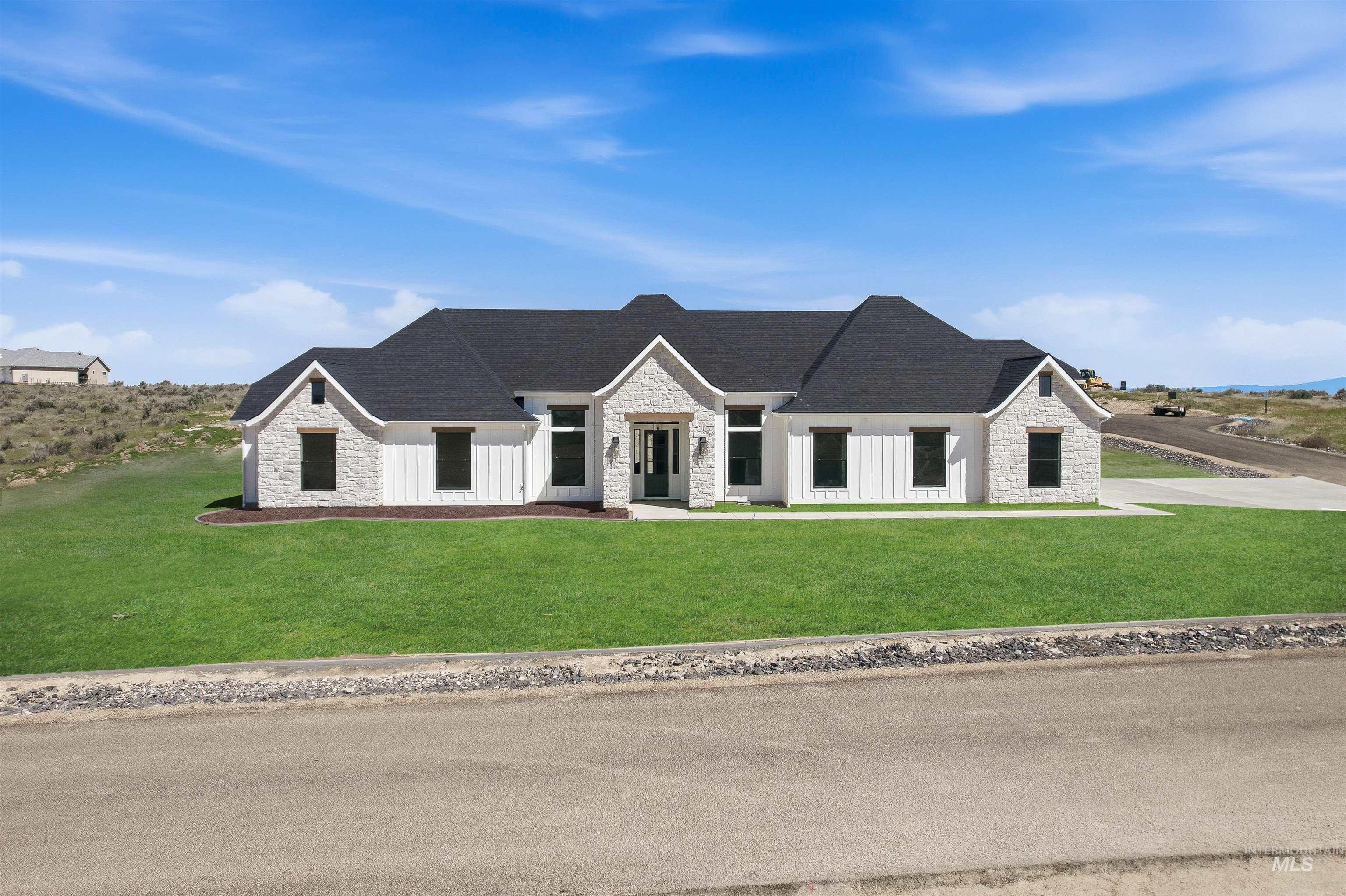 Modern farmhouse style home with stone siding, a front yard, and board and batten siding