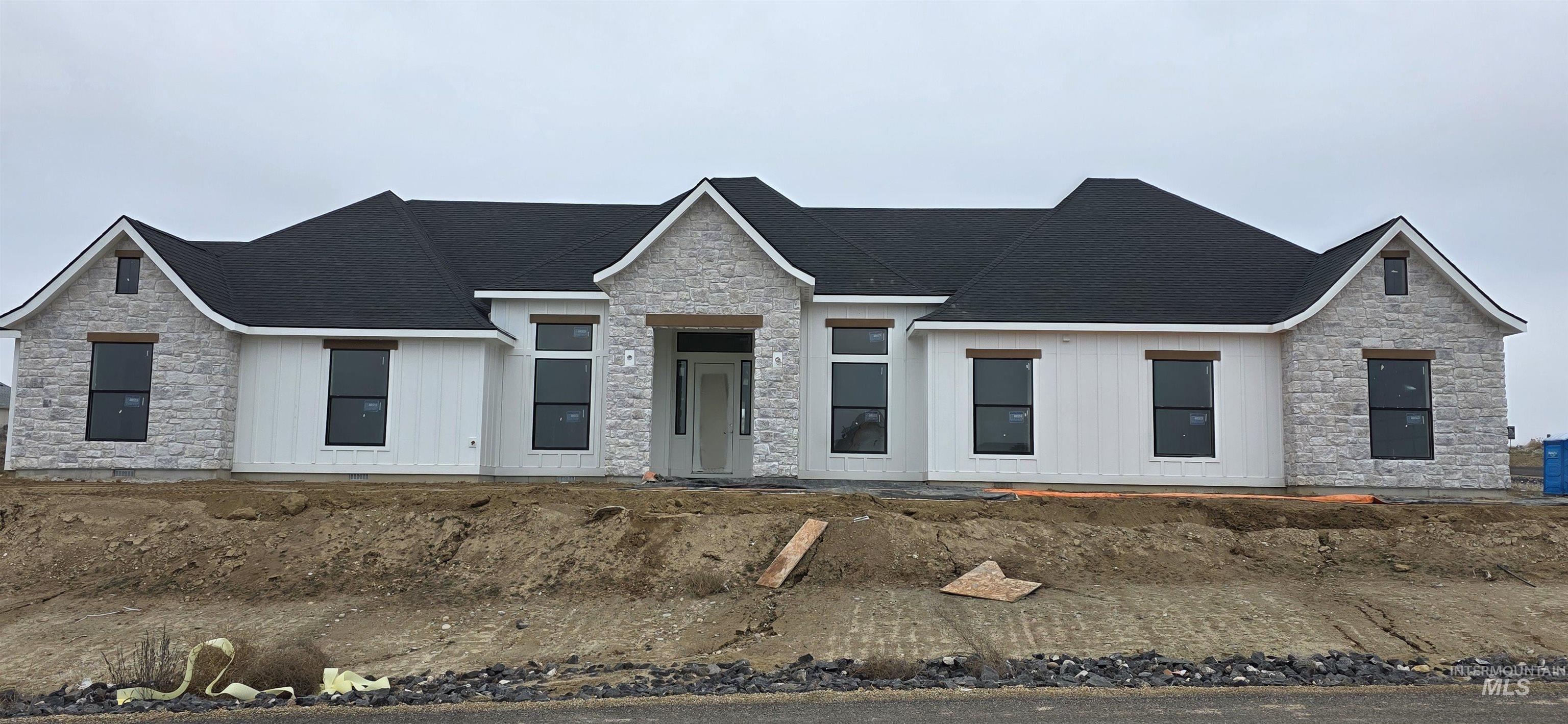 View of front of home featuring stone siding and a shingled roof