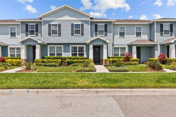 a front view of a house with a yard and potted plants