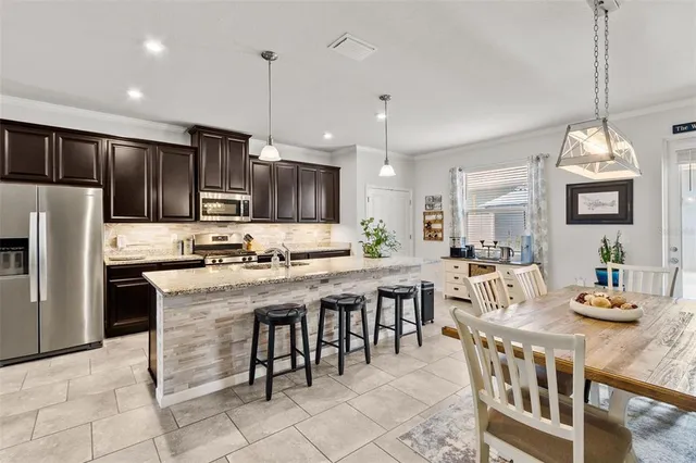 a kitchen with stainless steel appliances granite countertop a stove top oven a refrigerator a sink and a center island