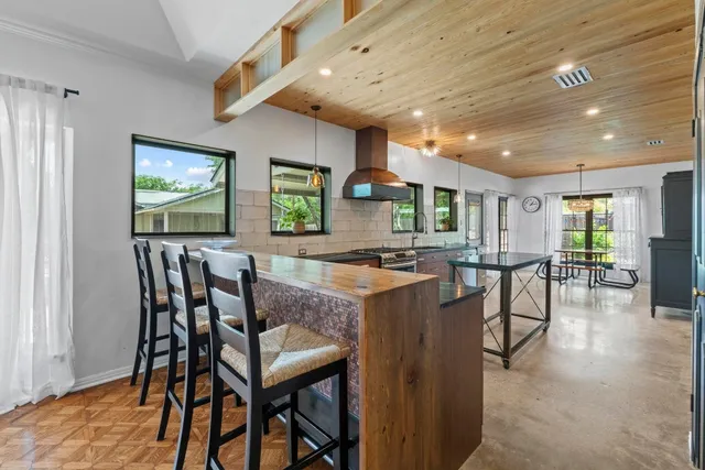 a kitchen with stainless steel appliances kitchen island granite countertop dining table chairs and a refrigerator