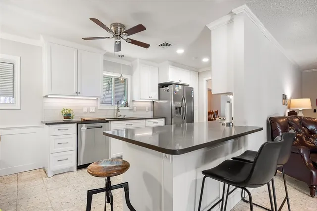 a kitchen with stainless steel appliances kitchen island granite countertop a table chairs and a refrigerator