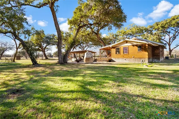 a view of backyard with large trees and a wooden fence