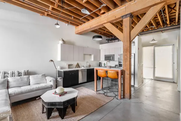 a living room with furniture a rug kitchen view and a chandelier
