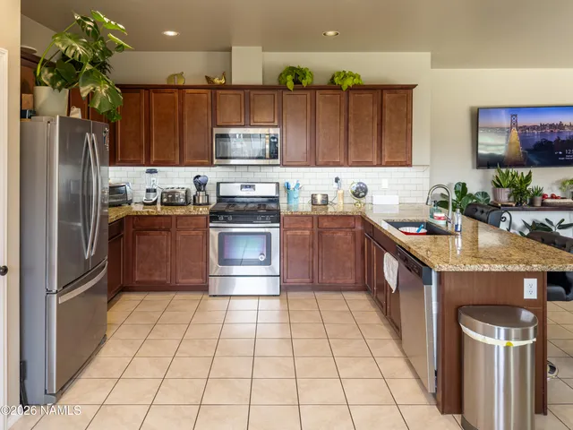 a kitchen with stainless steel appliances granite countertop a sink stove refrigerator and cabinets