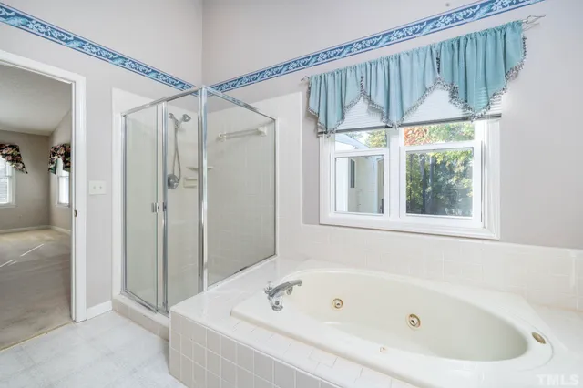 a bathroom with a bathtub a window and a shower