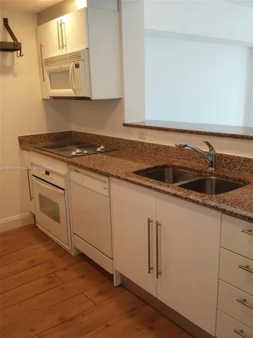 a kitchen with granite countertop white cabinets and white appliances