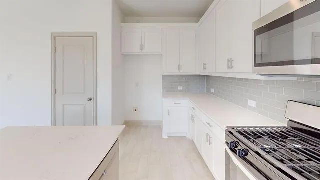 a kitchen with a stove and white cabinets