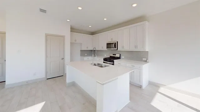 a kitchen with white cabinets and stainless steel appliances
