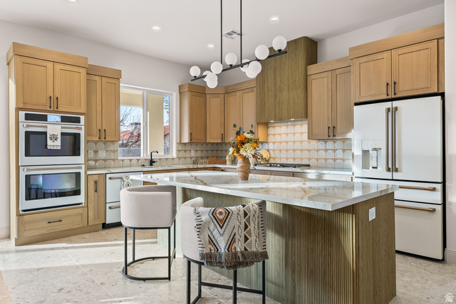 226 East 1100 North Hurricane, UT 84737 - Photo 20 of 49 Kitchen featuring white appliances, a kitchen island, light stone counters, a kitchen bar, and hanging light fixtures