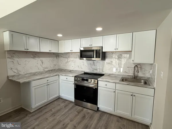 a kitchen with stainless steel appliances granite countertop a stove a sink and white cabinets
