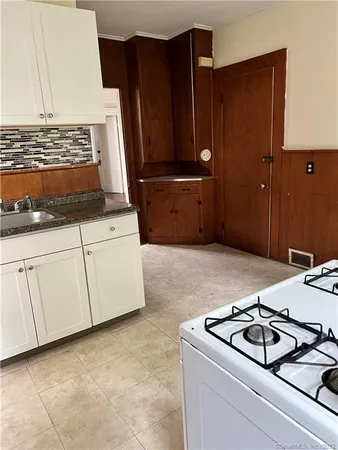 a kitchen with granite countertop a sink stove and cabinets