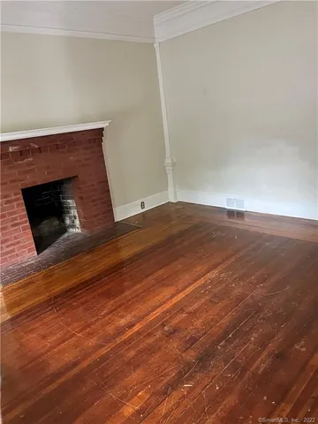 a view of empty room with wooden floor and fireplace