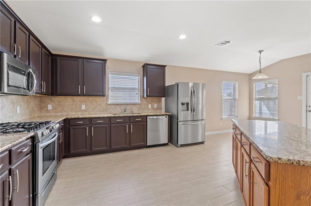 20224 Merlin Falcon Trail Pflugerville, TX 78660 - Photo 14 of 40 A well-equipped culinary space featuring rich wood cabinetry, stainless steel appliances, and durable tile flooring.