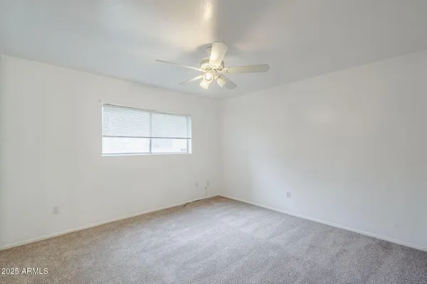 an empty room with a window and a ceiling fan