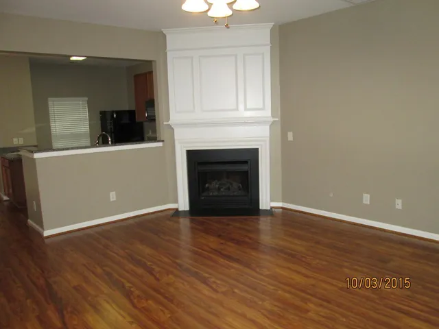 an empty room with wooden floor fireplace and windows