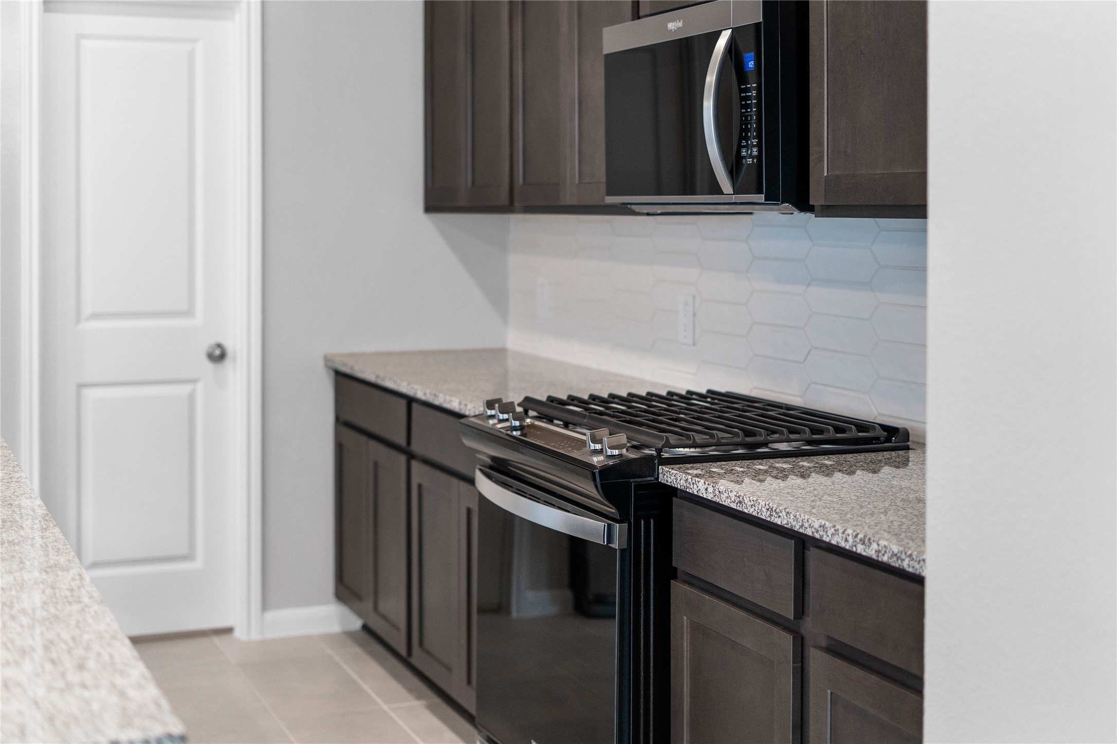 19555 Montgomery Rdg Way Montgomery, TX 77316 - Photo 16 of 38 Showcased here is a Whirlpool Gas range, paired with a steam microwave equipped with sensor cooking—all framed by an elegant tile backsplash.