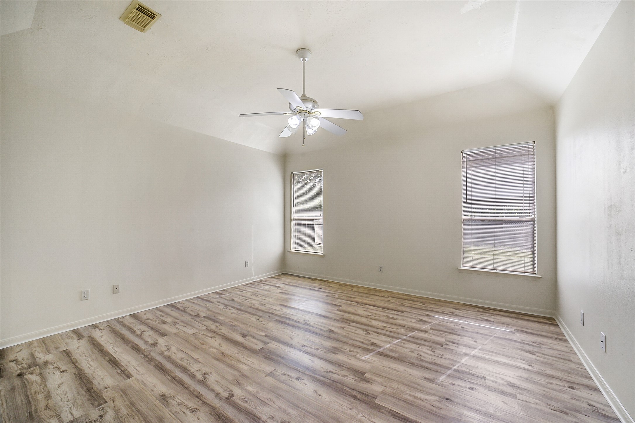 3502 Sweetspire Road Katy, TX 77449 - Photo 14 of 30 Spacious primary bedroom on the first floor featuring a vaulted ceiling that enhances the open, airy feel. The suite includes a large private bathroom and an expansive walk-in closet, offering both comfort and convenience in a well-designed retreat.