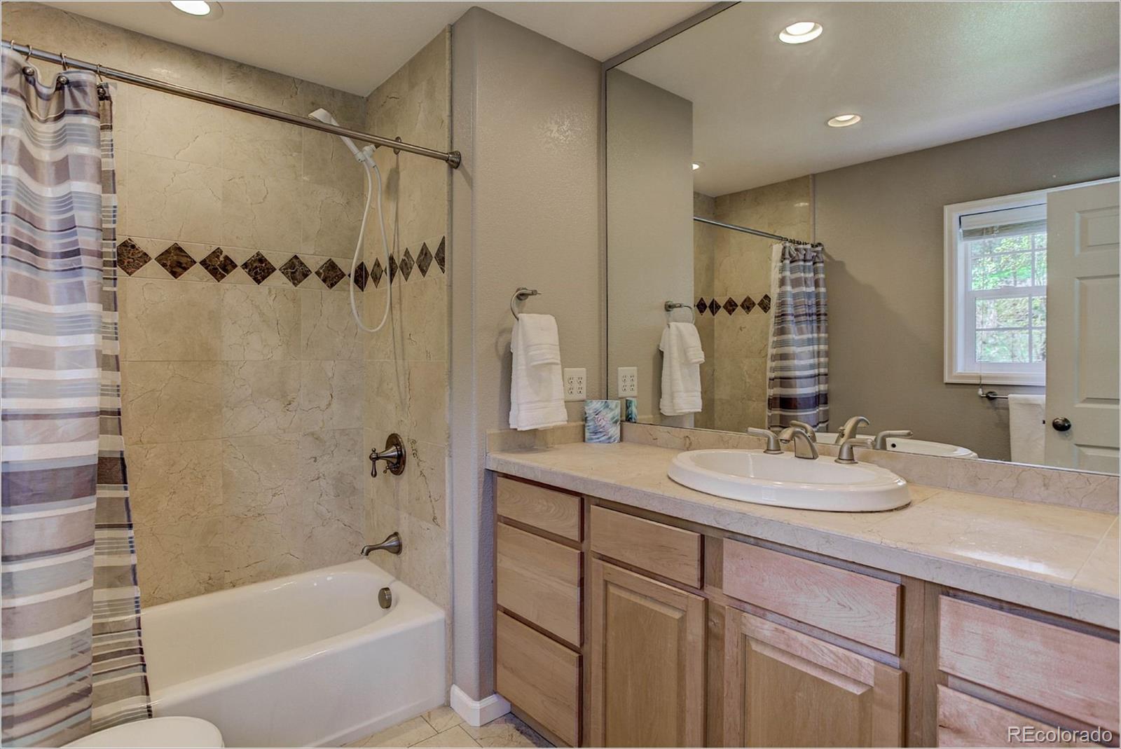 4961 Little Cub Creek Road Evergreen, CO 80439 - Photo 22 of 38 a bathroom with a granite countertop sink a mirror a bathtub and shower