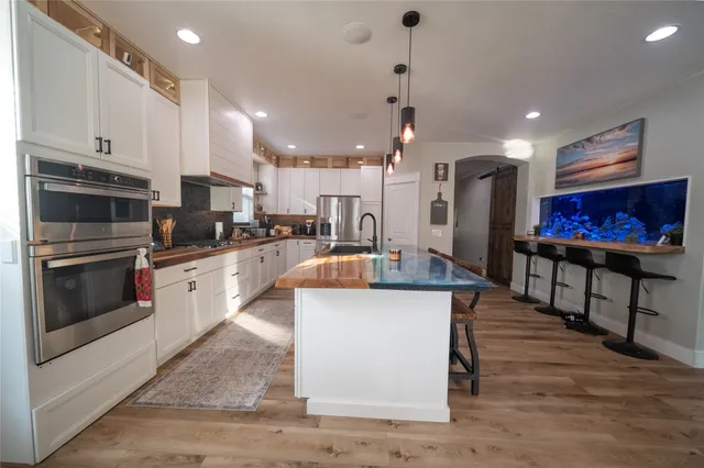 a kitchen with stainless steel appliances kitchen island granite countertop a stove top oven a sink a counter top space and cabinets