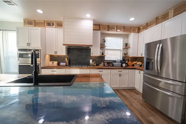 a kitchen with granite countertop a refrigerator and a stove top oven