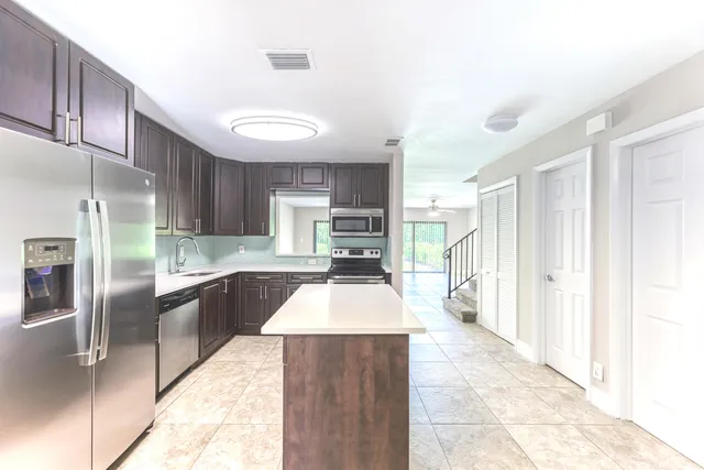 a large kitchen with stainless steel appliances granite countertop a refrigerator and a stove top oven