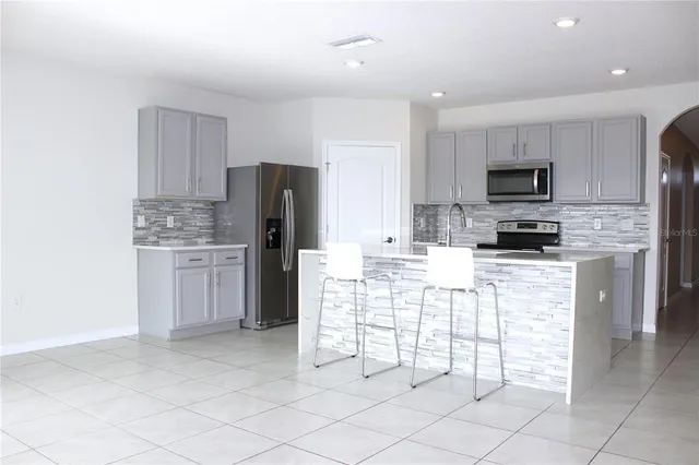 a kitchen with stainless steel appliances kitchen island granite countertop a refrigerator and a stove