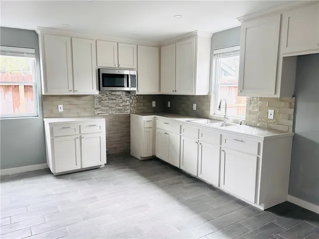 a kitchen with white cabinets appliances a sink and a window