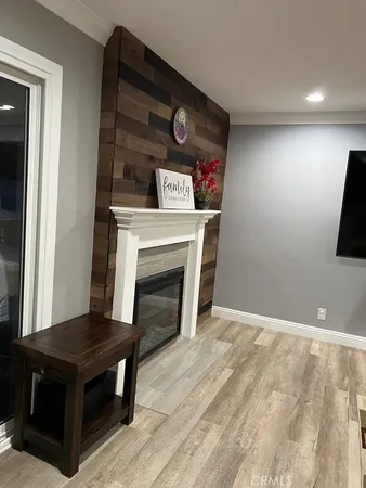 a view of an empty room with wooden floor and a fireplace