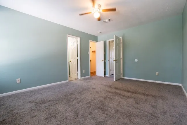 an empty room with chandelier fan and windows