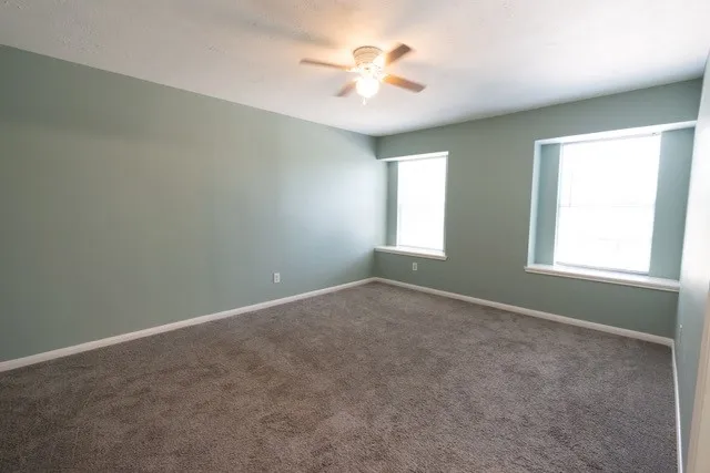 an empty room with a window and a fan