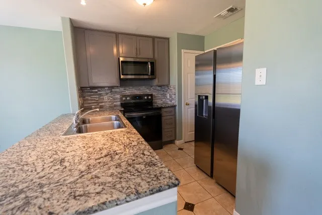 a kitchen with stainless steel appliances granite countertop a refrigerator and a stove top oven