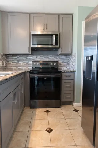 a kitchen with granite countertop a stove a microwave and a refrigerator